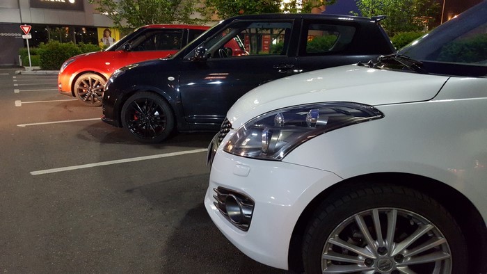 Three Suzuki Swift cars parked in a lot
