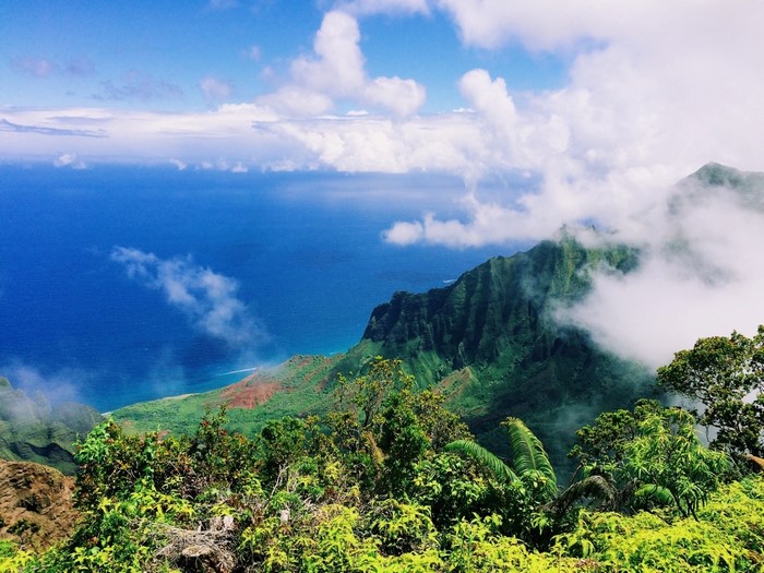 Green mountains overlooking the ocean with clouds