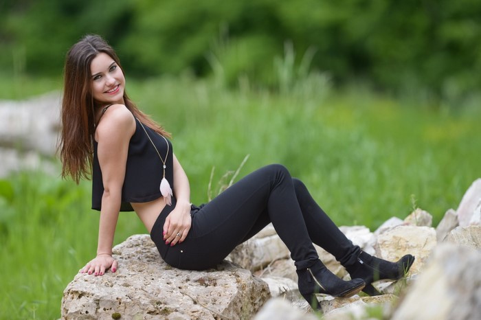 Woman in black clothing sitting on rocks outdoors