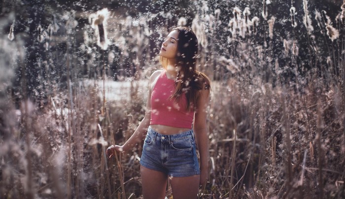 Woman in jean shorts standing in tall grass