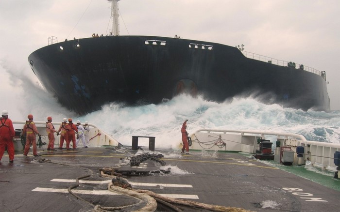 Ship in rough seas with crew members on deck