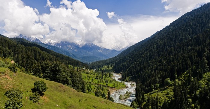 River flowing through a valley with forested mountains and snowy peaks