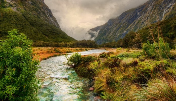River flowing through a mountain valley with clouds