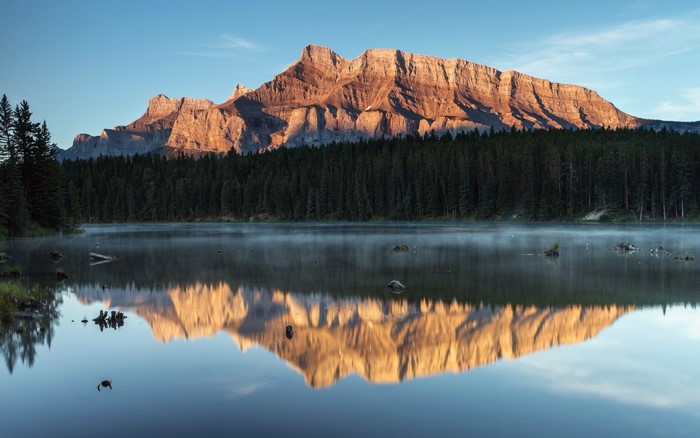 Mountain reflection in a misty lake at sunrise