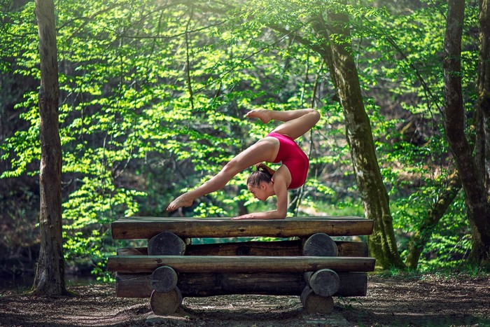 Flexible Woman in Red Leotard Balancing on Picnic Table