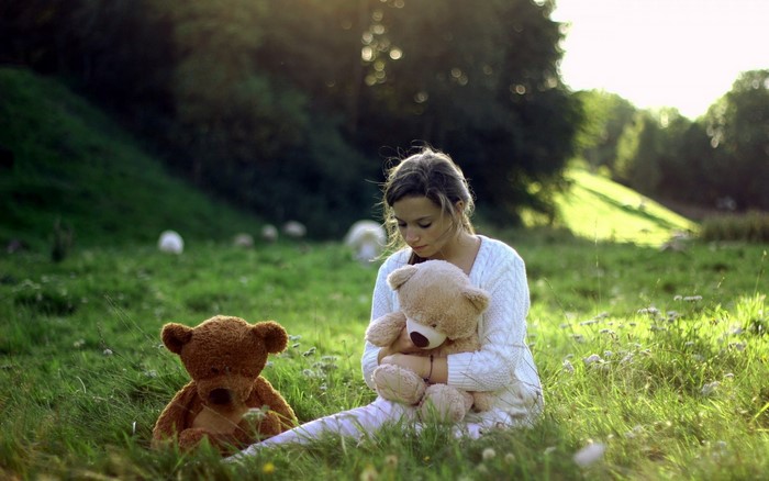 Girl with teddy bears in a grassy field