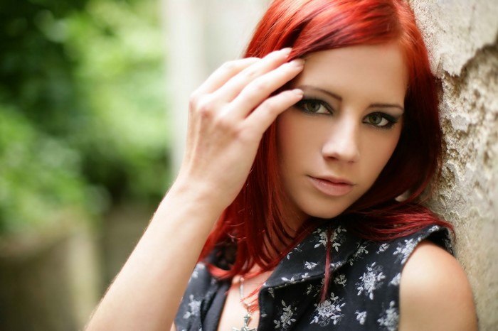 Woman with red hair leaning against a wall