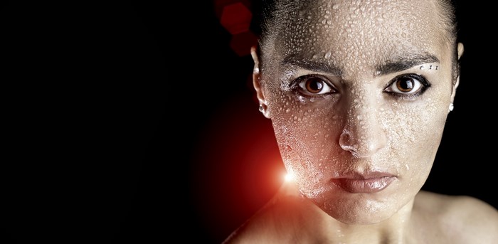 Woman's face covered in sweat with red lighting