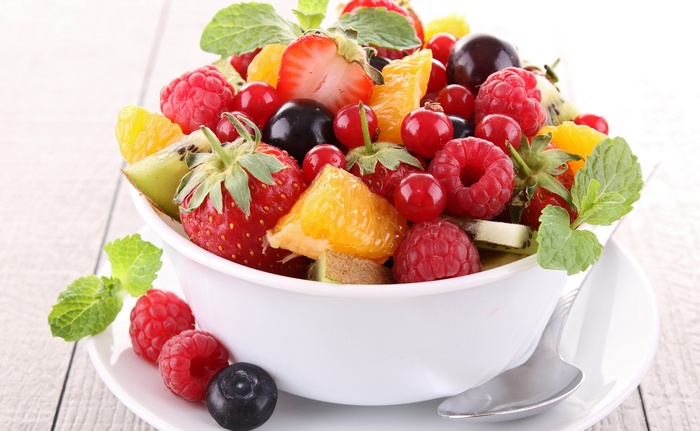 Fruit salad with strawberries, raspberries, blueberries, oranges, kiwi, and mint