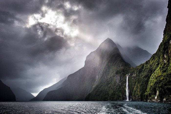 Waterfall in a Fjord with Mountains and Clouds
