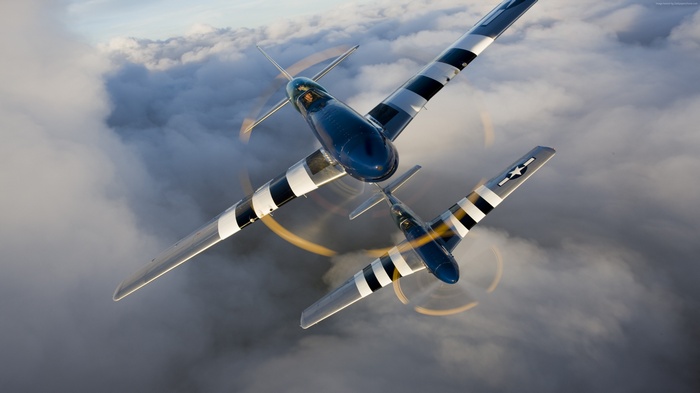 Two North American P-51 Mustangs flying through clouds