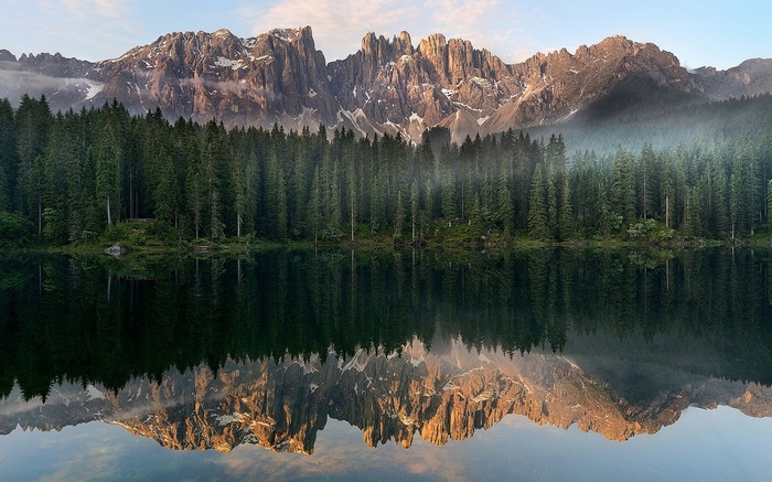 Lake reflection of pine forest and jagged mountains