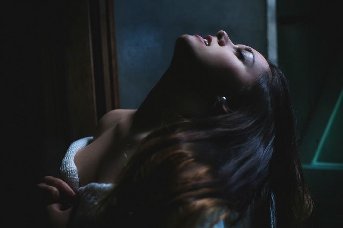 Woman with head tilted back in darkness