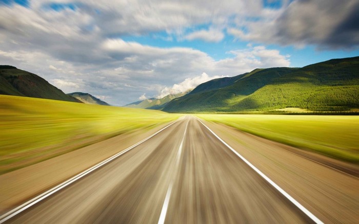 Road through green hills with motion blur