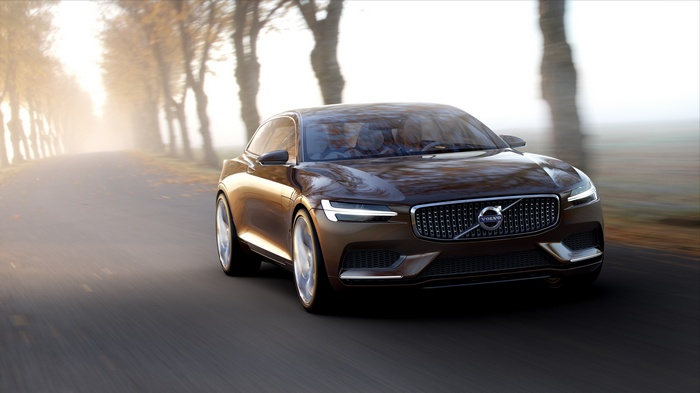 Brown Volvo S90 driving on a tree-lined road