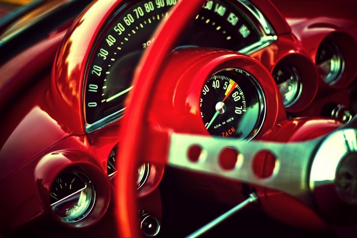 Close-up of a vintage red car dashboard and steering wheel