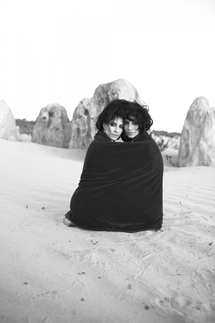 The Veronicas wrapped in a blanket on a sandy landscape