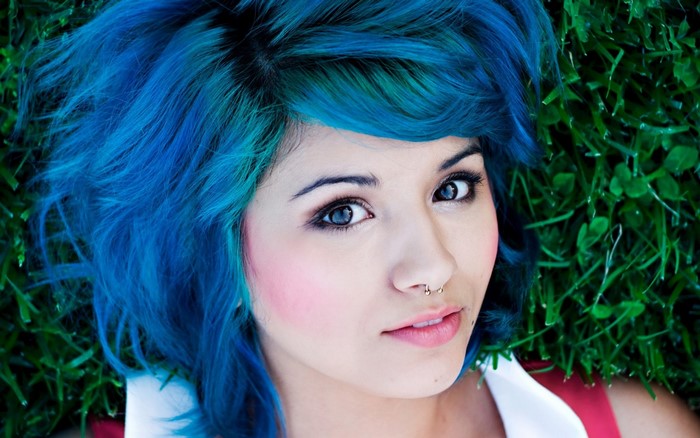 Woman with blue hair lying on grass