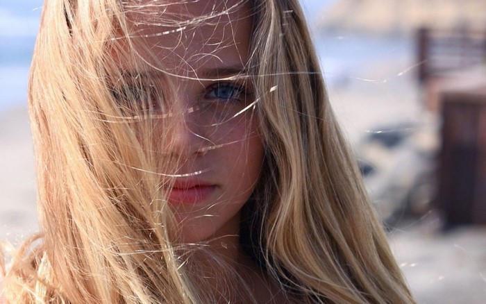 Close-up portrait of a young woman with blonde hair blowing in the wind