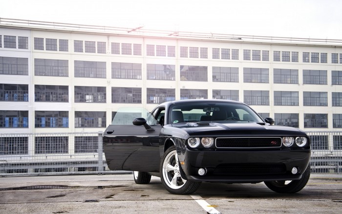 Black Dodge Challenger with open door in front of building