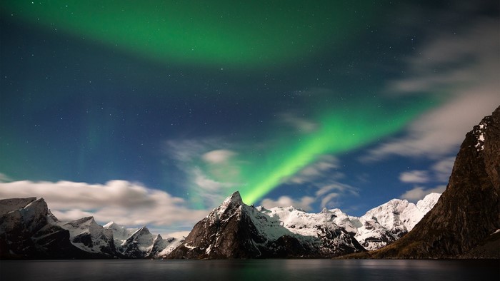 Aurora Borealis over snow-capped mountains and lake
