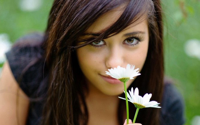 Young woman with brown hair holding daisies