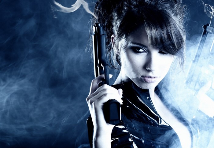 Woman holding a pistol with smoke