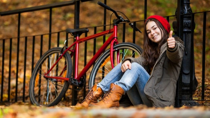 Woman in red beanie and coat with bicycle in autumn