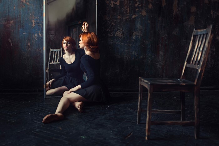 Woman in black dress sitting in front of a mirror