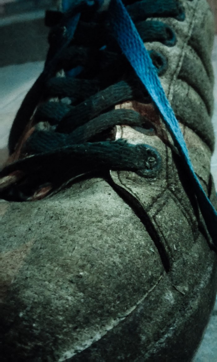 Close-up of a green and black shoe with blue laces