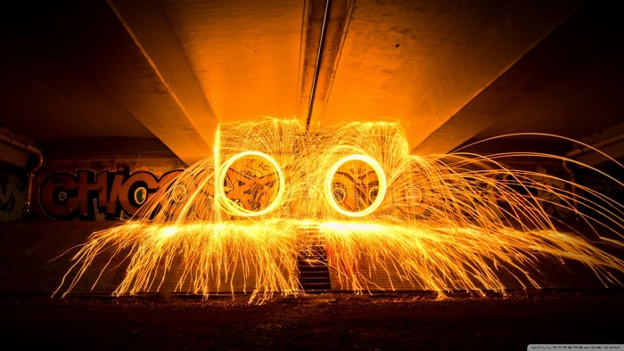 Steel wool spinning under a bridge with graffiti