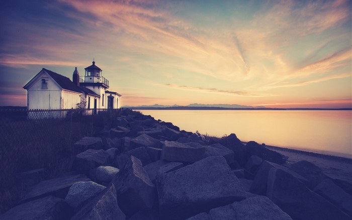 Lighthouse on a rocky shore at sunset