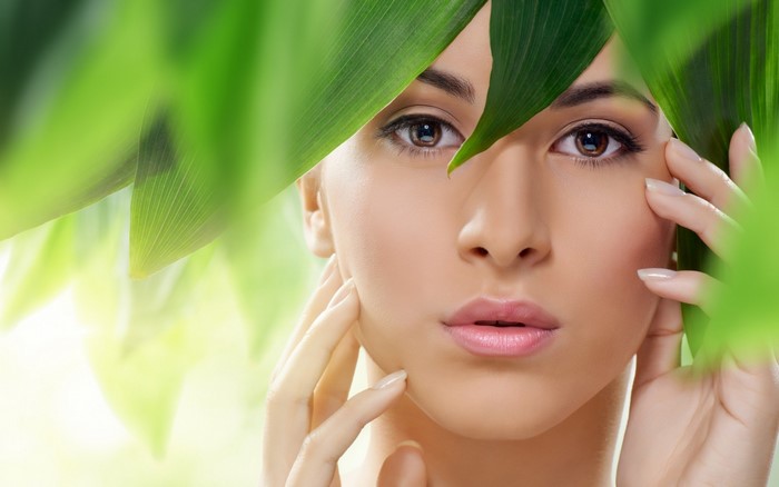 Woman's face with green leaves