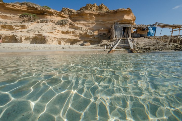 Wooden shack on a rocky beach with clear water
