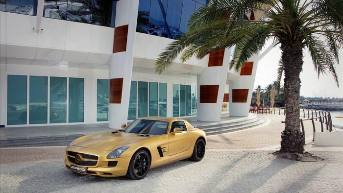 Gold Mercedes-Benz SLS AMG parked outside modern building