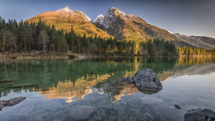 Mountains reflected in a lake with a forest and rocks
