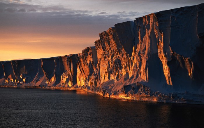 Sunset over Antarctic ice cliffs and ocean