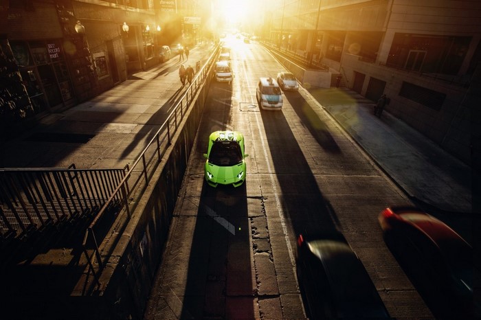 Green Lamborghini driving down a sunlit street