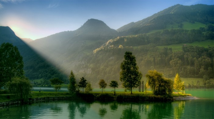 Sunlight beams over a misty mountain lake landscape