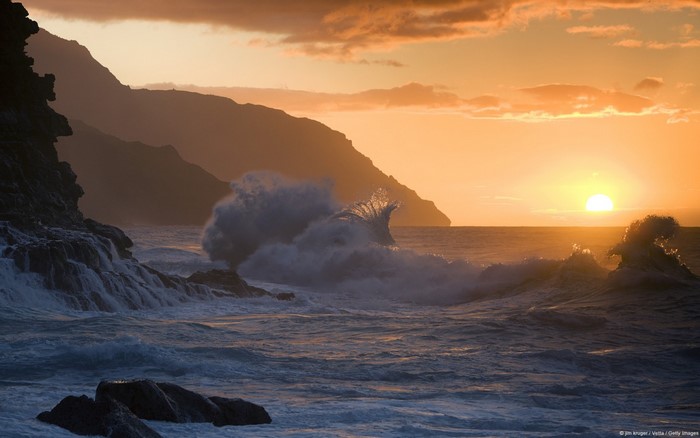 Waves crashing on rocky shore at sunset