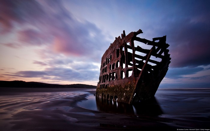 Shipwreck on a beach at sunset