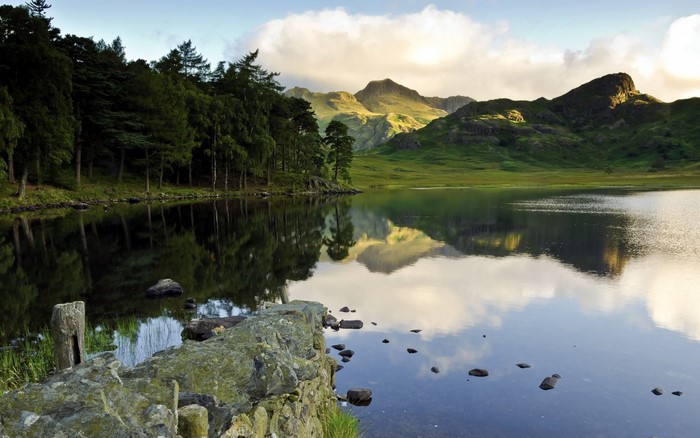 Lake reflection with trees and mountains at sunrise