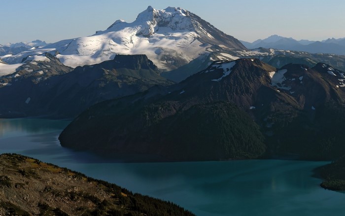 Snow-capped mountain range overlooking a turquoise lake
