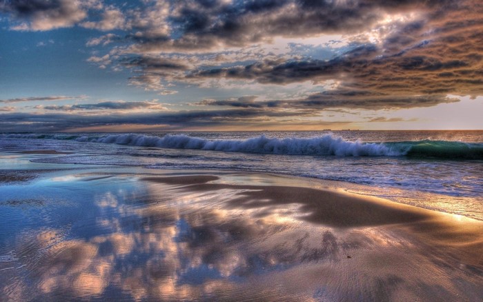 Sunset over the ocean with waves and reflections on the beach