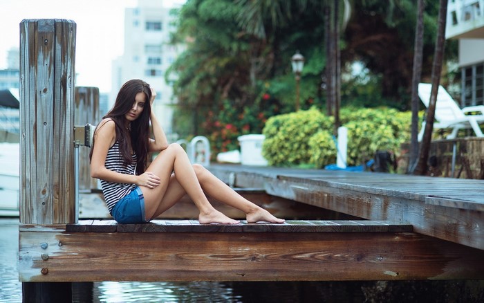 Woman sitting on a wooden dock by the water