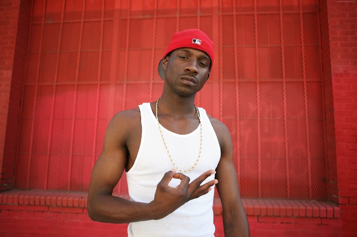 Jay Rock rapper wearing a white tank top and red hat