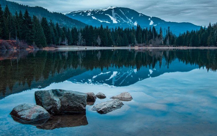Lake reflection of snow-capped mountains and evergreen forest