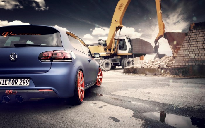 Blue Volkswagen Golf with orange wheels at construction site