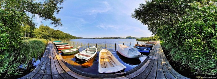 Boats docked on a wooden pier by a lake
