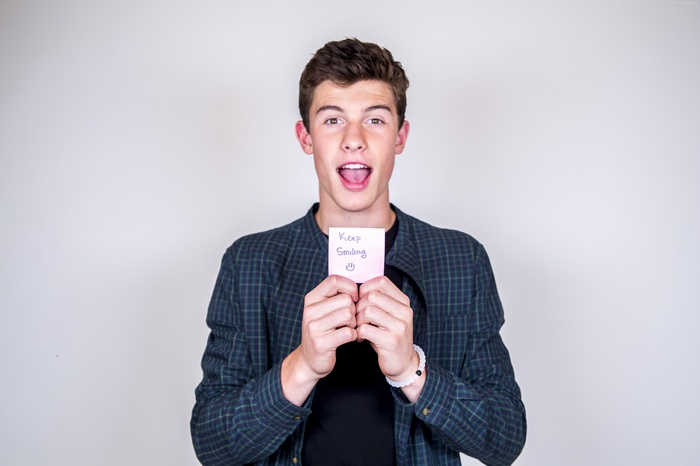 Shawn Mendes holding a 'Keep Smiling' note